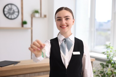Photo of Portrait of smiling receptionist giving guest room key in hotel
