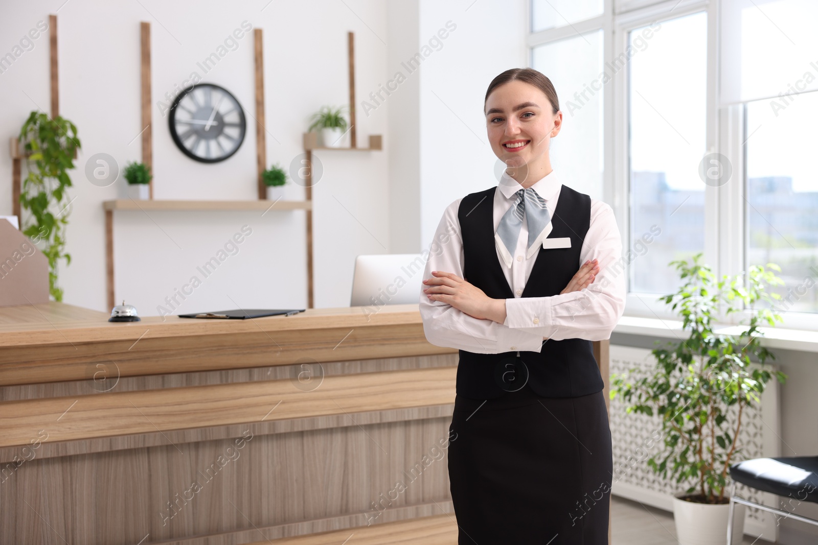 Photo of Portrait of smiling receptionist with crossed arms in hotel