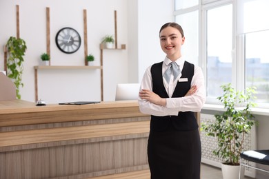 Photo of Portrait of smiling receptionist with crossed arms in hotel