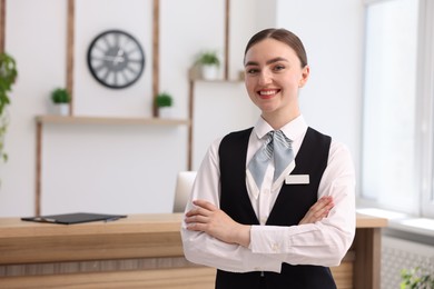 Photo of Portrait of smiling receptionist with crossed arms in hotel