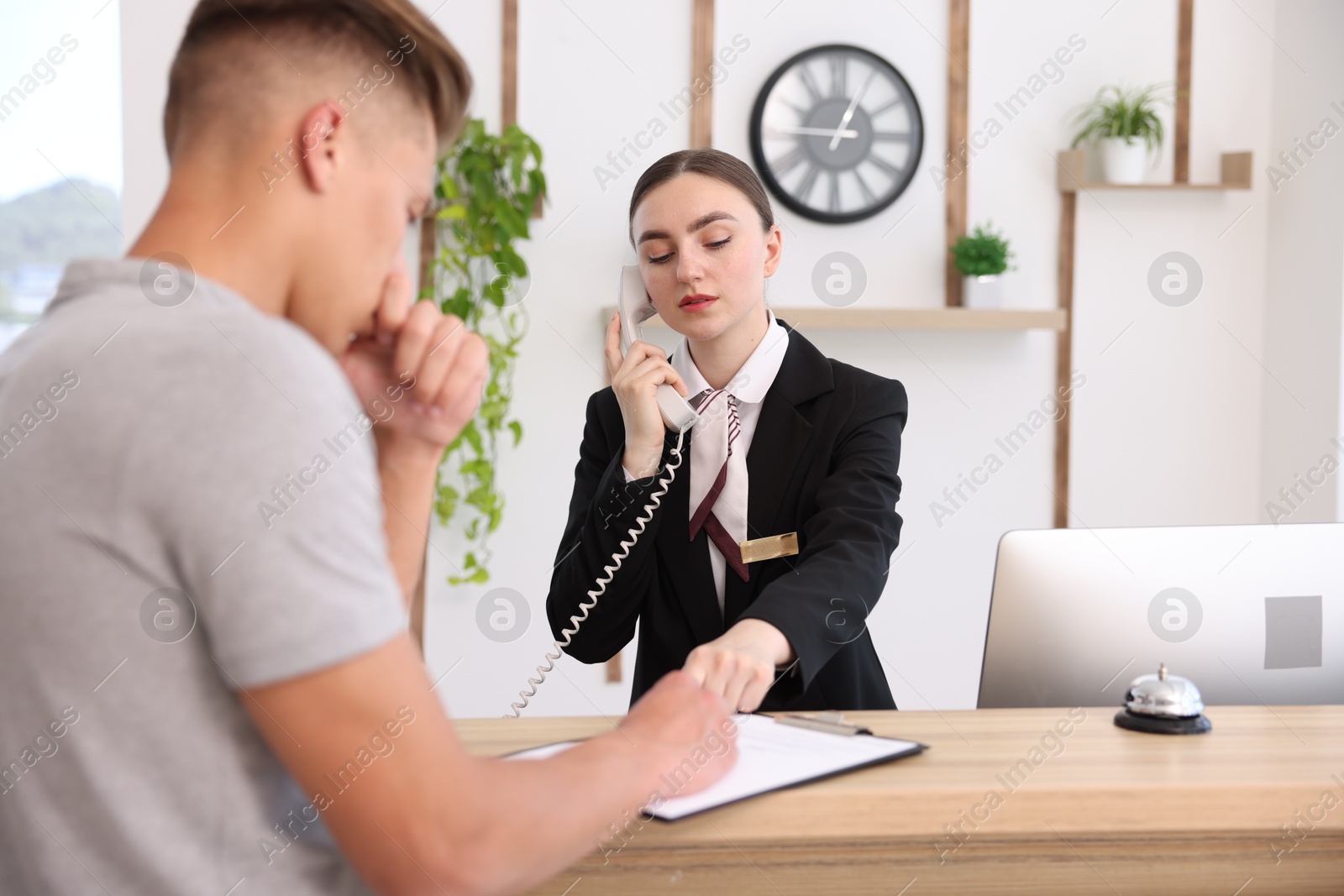 Receptionist working with client at reception desk in hotel Photo of Receptionist working with client at reception desk in hotel