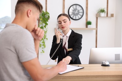 Photo of Receptionist working with client at reception desk in hotel