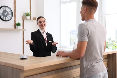 Photo of Smiling receptionist working with client at reception desk in hotel