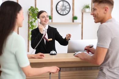 Photo of Smiling receptionist working with clients at reception desk in hotel