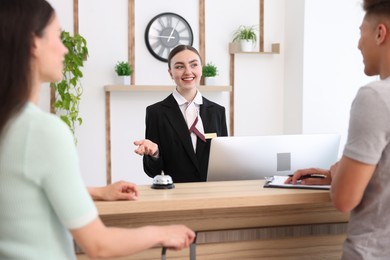 Photo of Smiling receptionist working with clients at reception desk in hotel