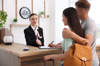 Photo of Receptionist working with clients at reception desk in hotel