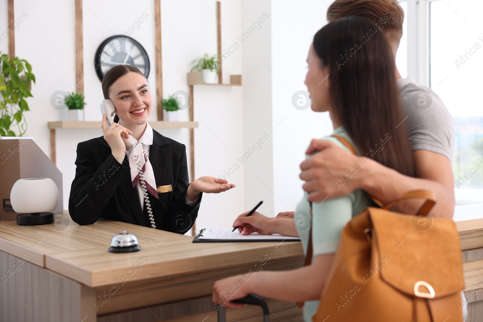 Smiling receptionist working with clients at reception desk in hotel Photo of Smiling receptionist working with clients at reception desk in hotel