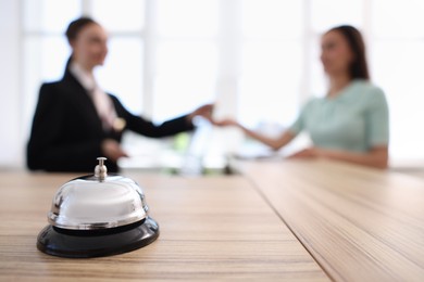Photo of Receptionist working with client in hotel, focus on service bell