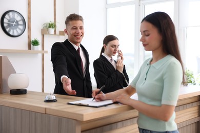 Photo of Receptionists and client at reception desk in hotel