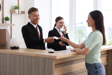 Photo of Smiling receptionists and client at reception desk in hotel