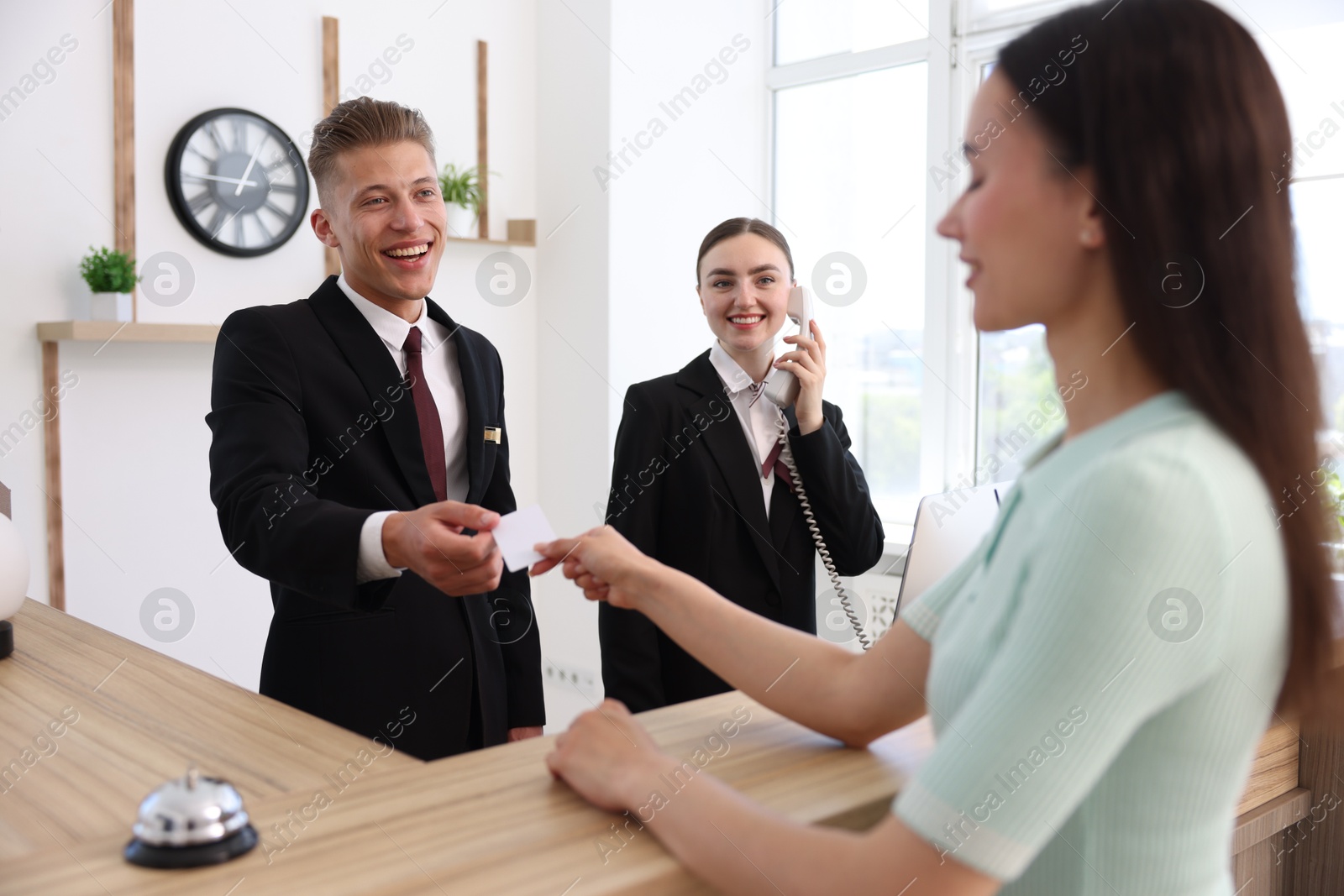 Receptionists and client at reception desk in hotel Photo of Receptionists and client at reception desk in hotel
