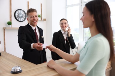 Photo of Receptionists and client at reception desk in hotel