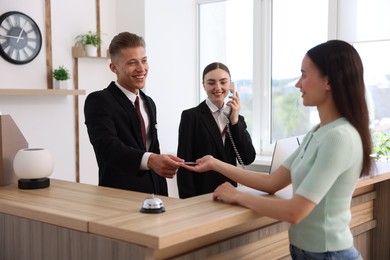 Photo of Receptionists and client at reception desk in hotel