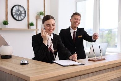 Photo of Smiling receptionists working at reception desk in hotel