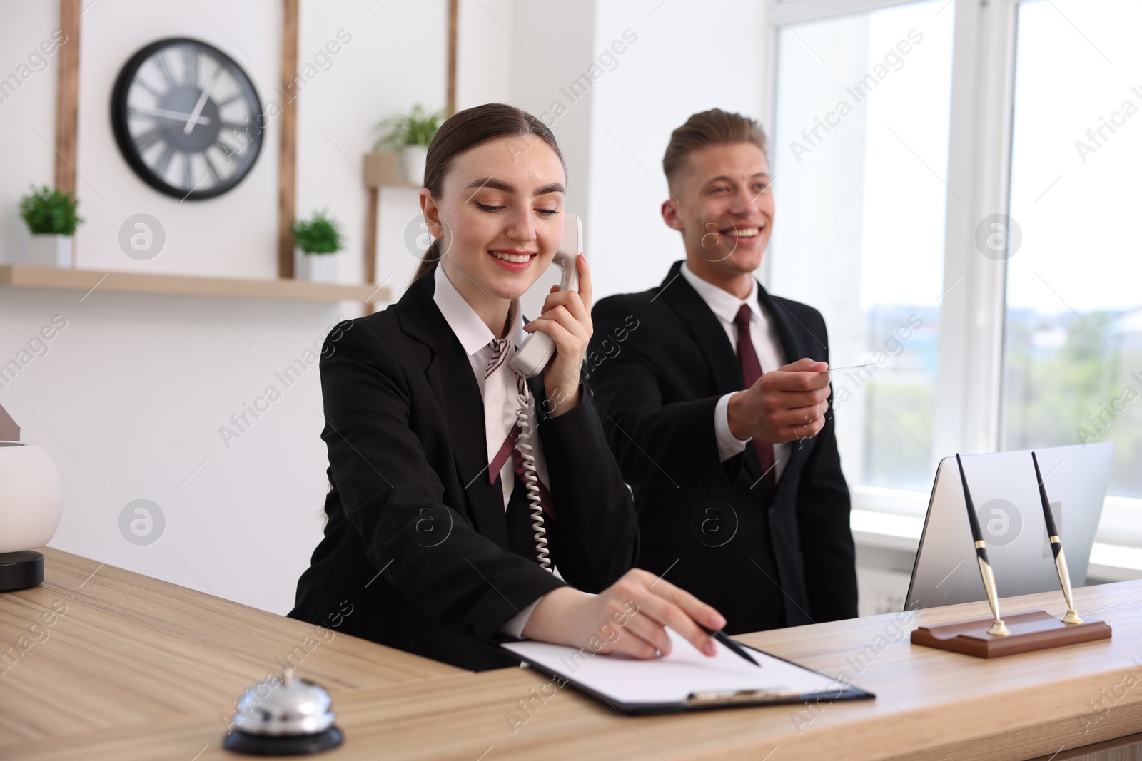 Smiling receptionists working at reception desk in hotel Photo of Smiling receptionists working at reception desk in hotel