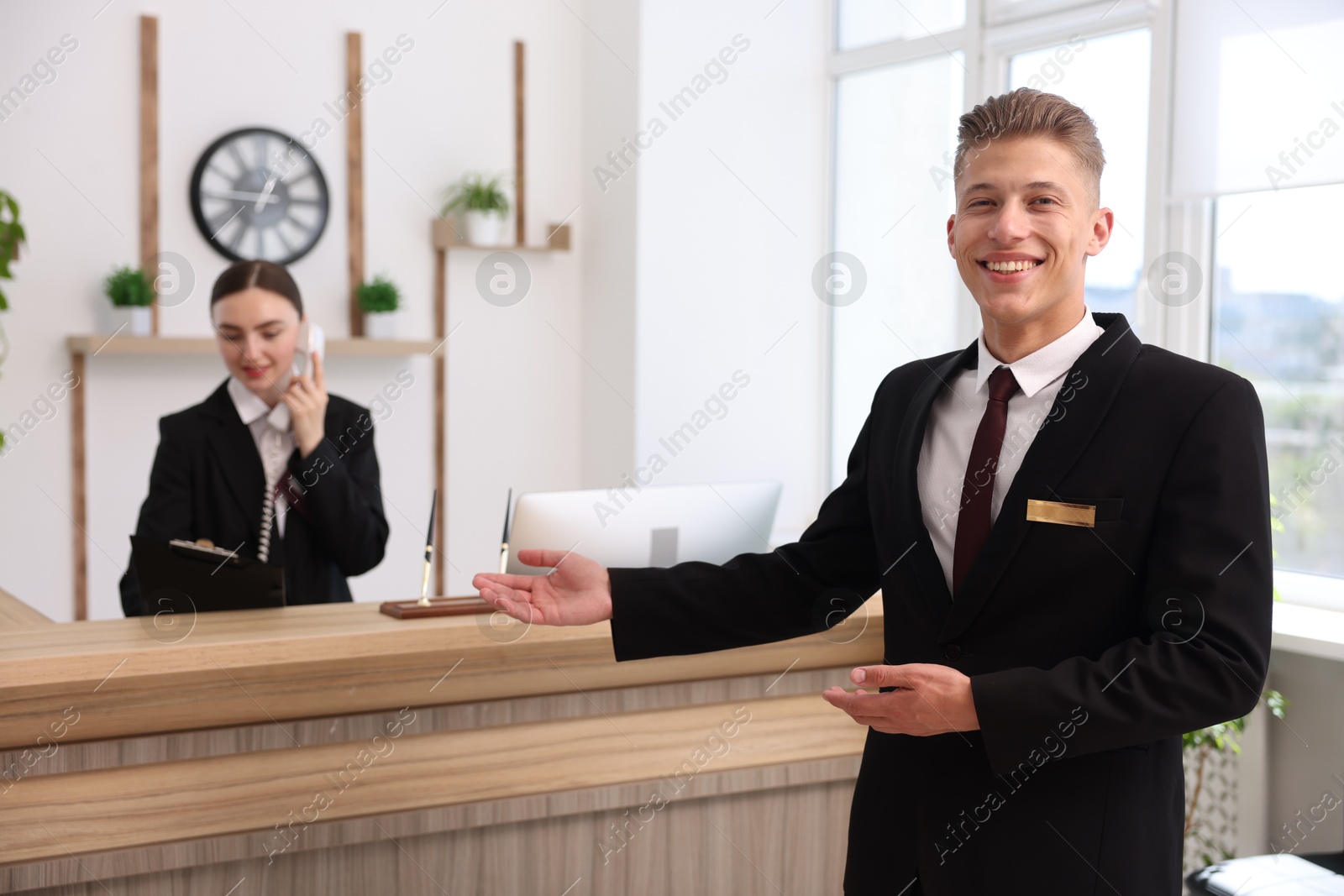 Photo of Smiling receptionist in uniform and his colleague working in hotel, selective focus