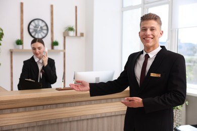 Photo of Smiling receptionist in uniform and his colleague working in hotel, selective focus