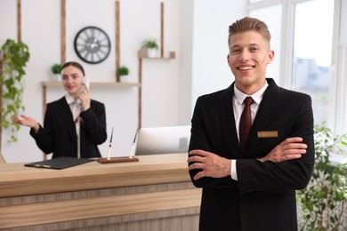 Photo of Smiling receptionist in uniform and his colleague working in hotel, selective focus