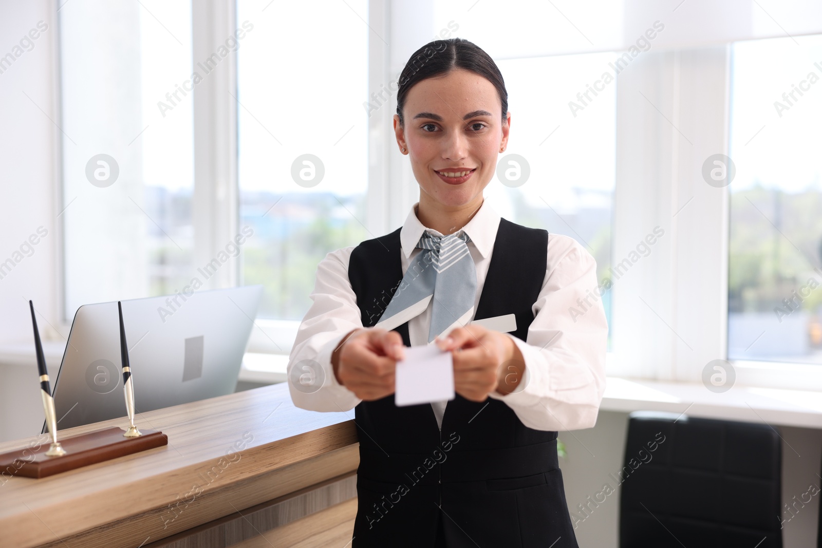 Smiling receptionist in uniform giving key card in hotel Photo of Smiling receptionist in uniform giving key card in hotel