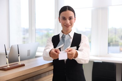 Photo of Smiling receptionist in uniform giving key card in hotel