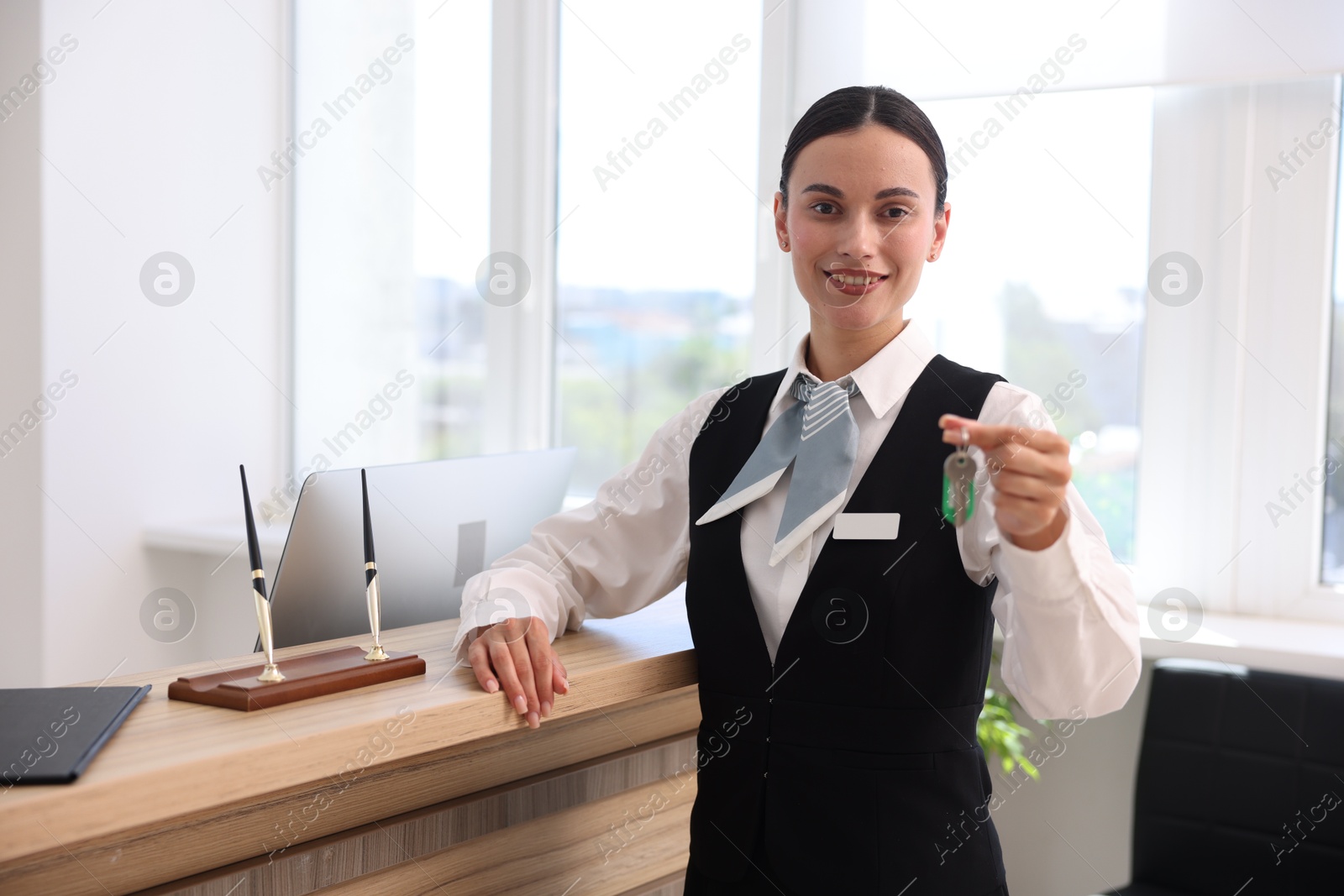 Smiling receptionist in uniform giving guest room key in hotel Photo of Smiling receptionist in uniform giving guest room key in hotel
