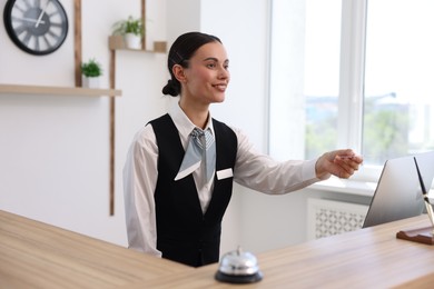 Photo of Smiling receptionist in uniform giving card key at reception desk in hotel