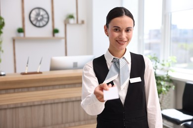 Photo of Smiling receptionist in uniform giving key card in hotel. Space for text