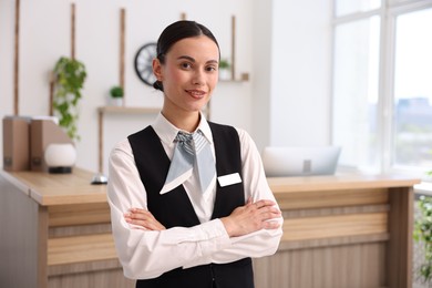 Photo of Portrait of smiling receptionist with crossed arms in hotel