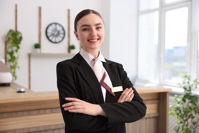 Photo of Portrait of smiling receptionist with crossed arms in hotel
