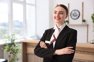 Photo of Portrait of smiling receptionist with crossed arms in hotel