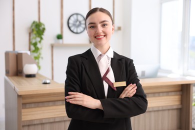 Photo of Portrait of smiling receptionist with crossed arms in hotel