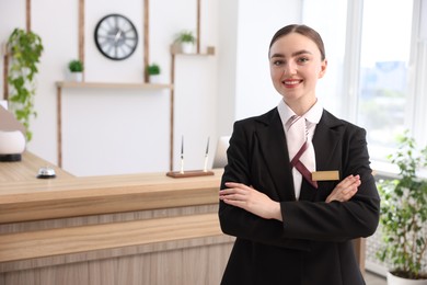 Photo of Portrait of smiling receptionist with crossed arms in hotel