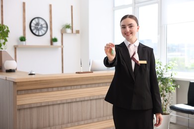 Photo of Smiling receptionist in uniform giving guest room key in hotel