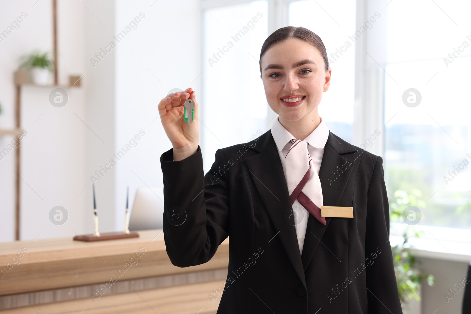 Smiling receptionist in uniform giving guest room key in hotel Photo of Smiling receptionist in uniform giving guest room key in hotel