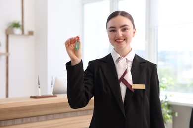 Photo of Smiling receptionist in uniform giving guest room key in hotel