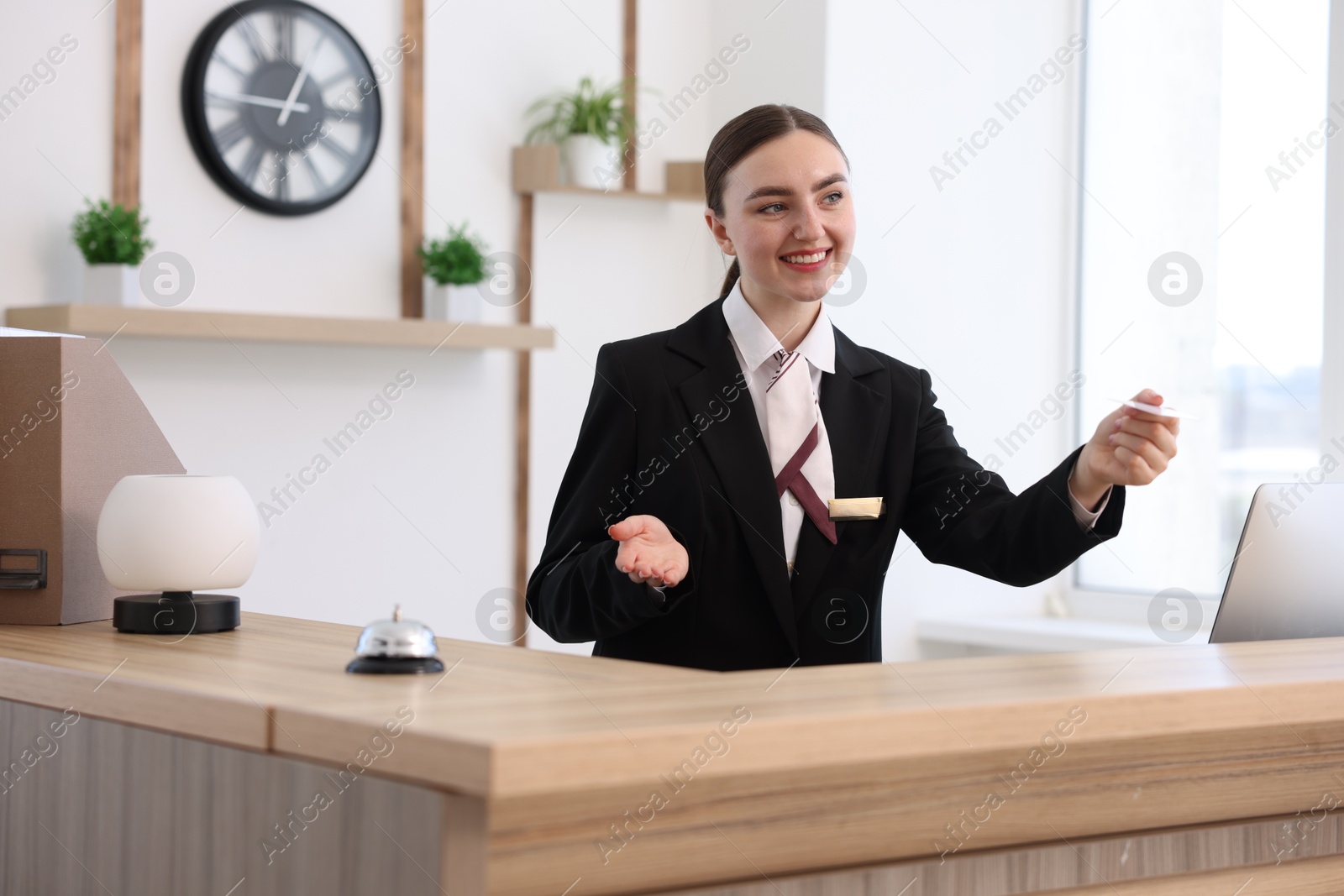 Smiling receptionist in uniform giving card key at reception desk in hotel Photo of Smiling receptionist in uniform giving card key at reception desk in hotel