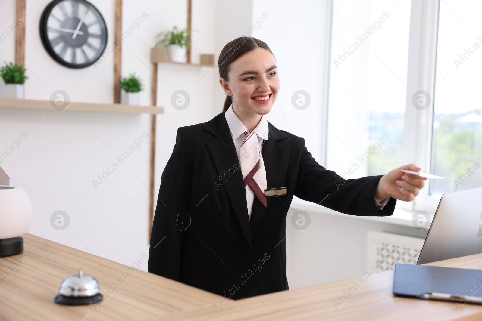 Smiling receptionist in uniform giving card key at reception desk in hotel Photo of Smiling receptionist in uniform giving card key at reception desk in hotel