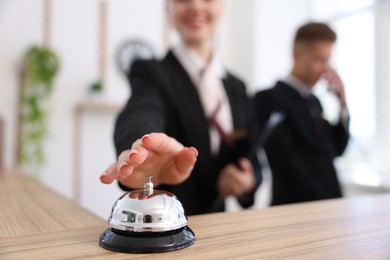 Photo of Client pushing service bell at reception desk in hotel, closeup