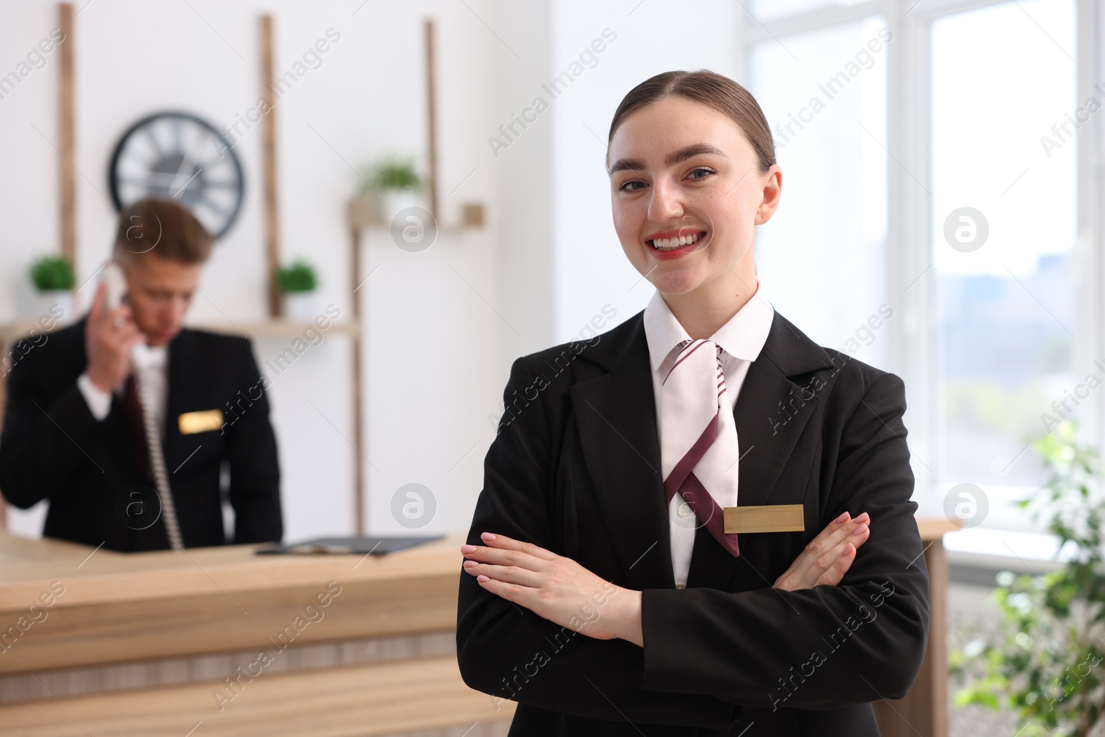 Smiling receptionist in uniform and her colleague working in hotel, selective focus Photo of Smiling receptionist in uniform and her colleague working in hotel, selective focus