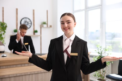 Photo of Smiling receptionist in uniform and her colleague working in hotel, selective focus