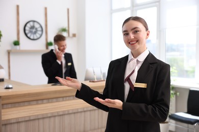 Photo of Smiling receptionist in uniform and her colleague working in hotel, selective focus