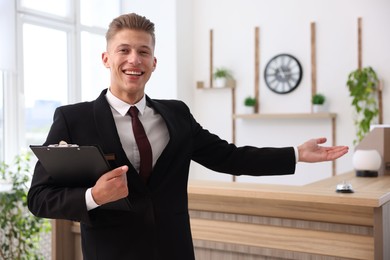 Photo of Portrait of smiling receptionist with clipboard in hotel