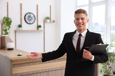 Photo of Portrait of smiling receptionist with clipboard in hotel