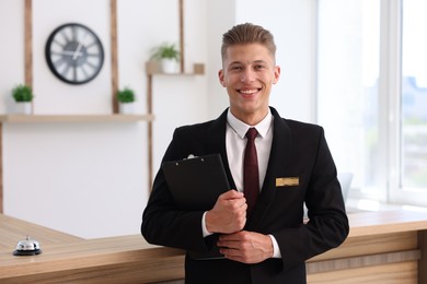 Photo of Portrait of smiling receptionist with clipboard in hotel