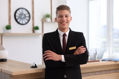 Photo of Portrait of smiling receptionist with crossed arms in hotel