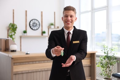 Photo of Smiling receptionist in uniform giving guest room key in hotel