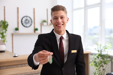 Photo of Smiling receptionist in uniform giving guest room key in hotel