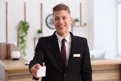 Photo of Smiling receptionist in uniform giving key card in hotel