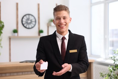 Photo of Smiling receptionist in uniform giving key card in hotel