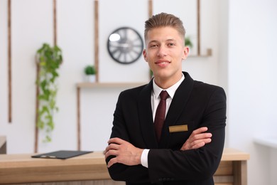 Photo of Portrait of smiling receptionist with crossed arms in hotel